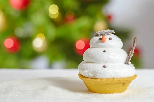 Snowman cookie and christmas tree behind — Stock Photo, Image