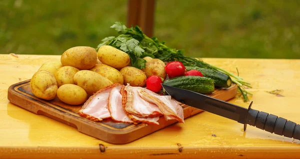 Fresh raw potatoes with meat and vegetables and knife on wooden table — Stock Photo, Image