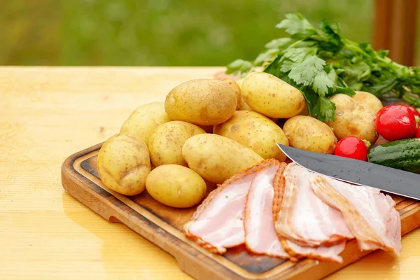 Fresh raw potatoes with meat and vegetables and knife on wooden table — Stock Photo, Image