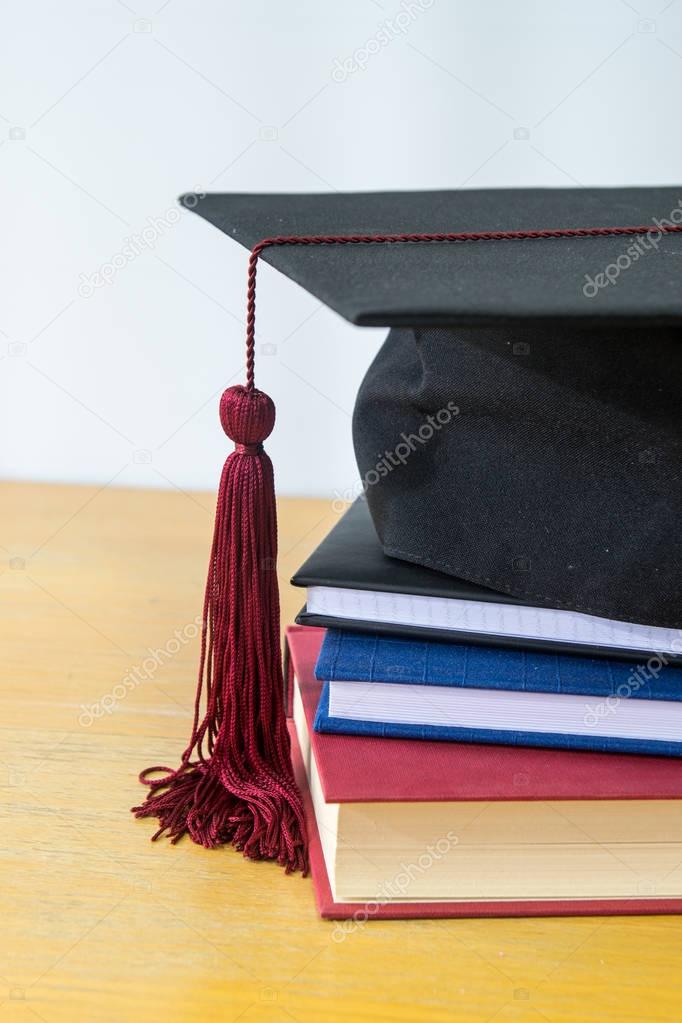 Closeup on black bonnet for graduation ceremony on top of books