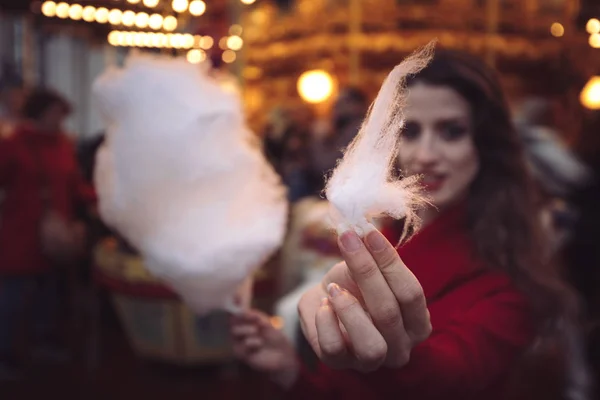 Portrait of a beautiful young girl with white cotton candy in fr