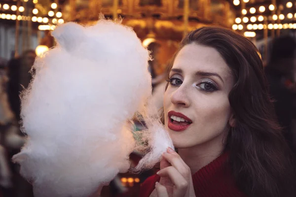 Portrait of a beautiful young girl with white cotton candy in fr