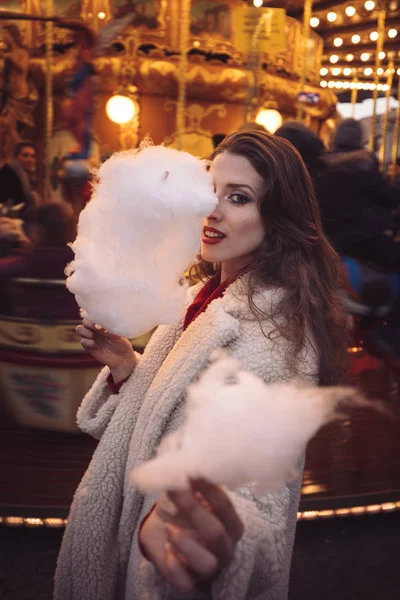 Portrait of a beautiful young girl with white cotton candy in fr