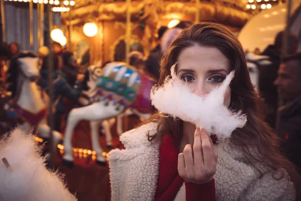 Portrait of a beautiful young girl with white cotton candy in fr