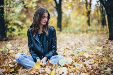 Kız sonbahar parkında yürüyor.