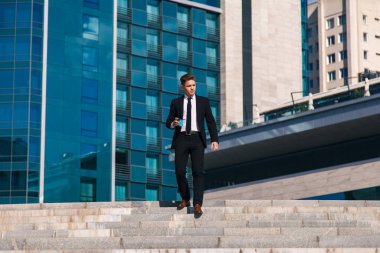 Genç işadamı sokakta kahve içiyor ve toplantı bekliyor.