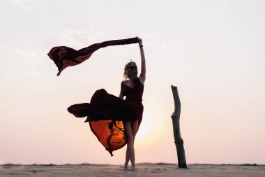 Rüzgâr çölde bir kızın elbisesini şişiriyor.