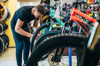 Adam bisiklet atölyesinde bisiklet tamir ediyor.