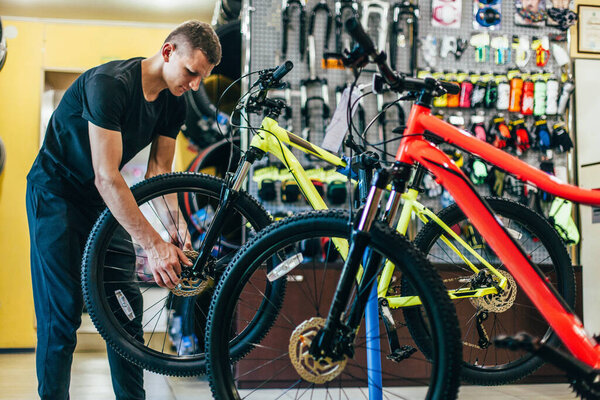 Guy is repairing a bicycle in a bicycle workshop