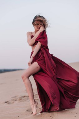 Kumaşlı kız çölde rüzgarda duruyor.