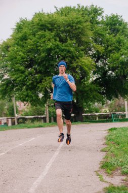 Genç adam sabah stadyumunda antrenman yapıyor.