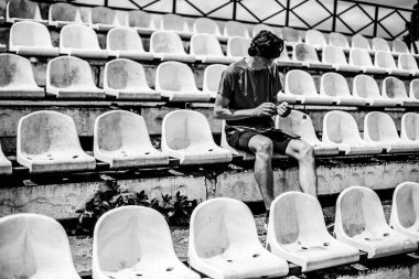 Genç adam koşudan sonra stadyumun podyumunda dinleniyor.