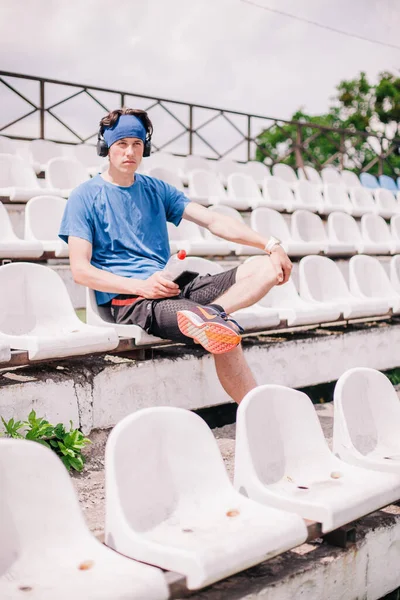 young guy is resting on the podium of the stadium after running