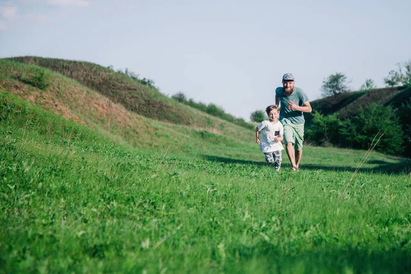 Táta a syn pobíhají po trávě — Stock fotografie