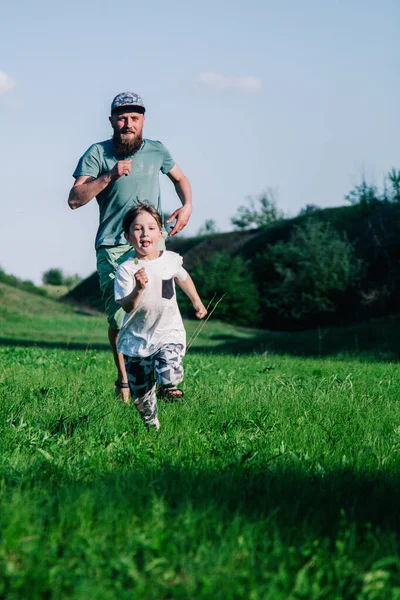 Táta a syn pobíhají po trávě — Stock fotografie