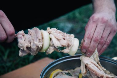 Barbekü için bir şişe salamura edilmiş et bağlayan bir adam.