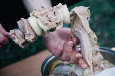 Barbekü için bir şişe salamura edilmiş et bağlayan bir adam.