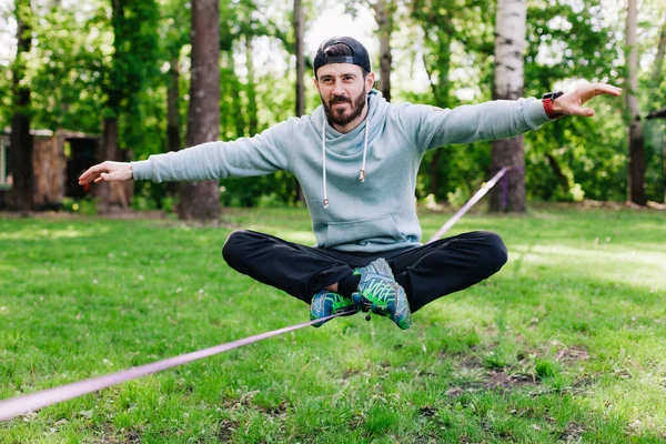 남자가 래프트 라인에서 균형을 있어요 공원에서 밧줄에 균형을 — 스톡 사진