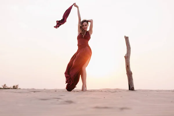 Silhouette di una ragazza in abito rosso al tramonto nel deserto — Foto Stock
