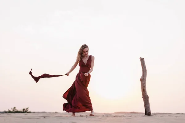 Silhouette di una ragazza in abito rosso al tramonto nel deserto — Foto Stock