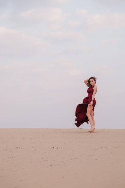 Çölde gün batımında kırmızı elbiseli bir kız.