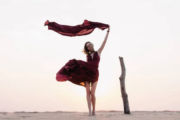 Silueta de una chica vestida de rojo al atardecer en el desierto — Foto de Stock