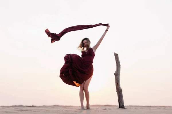 Silhueta de uma menina em um vestido vermelho ao pôr do sol no deserto — Fotografia de Stock