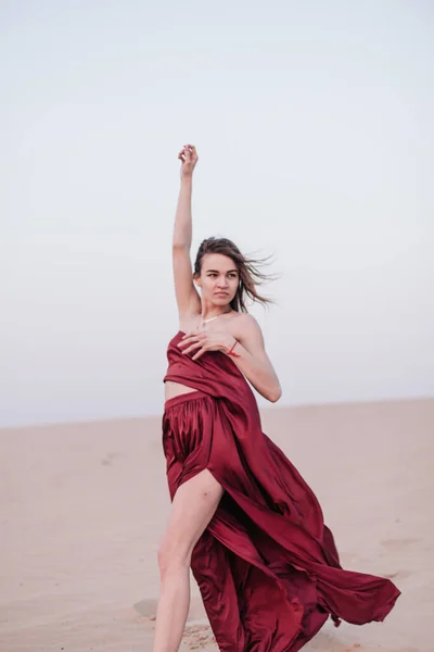 Chica con tela roja en los rayos del atardecer en el desierto —  Fotos de Stock