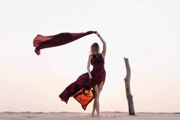 Silueta de una chica vestida de rojo al atardecer en el desierto — Foto de Stock