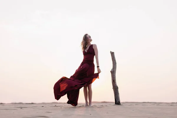 Silueta de una chica vestida de rojo al atardecer en el desierto — Foto de Stock