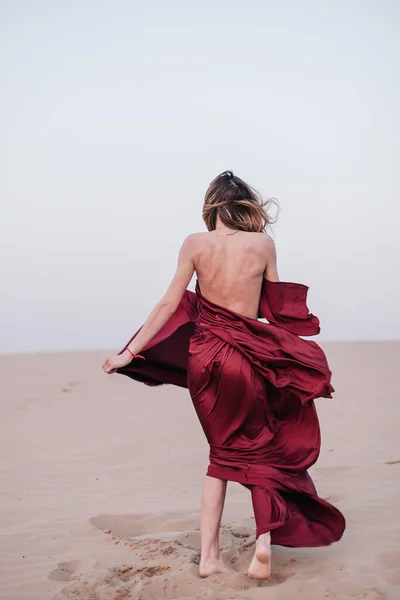 해질 녘에 붉은 옷을 입고 사막에서 노는 소녀 — 스톡 사진