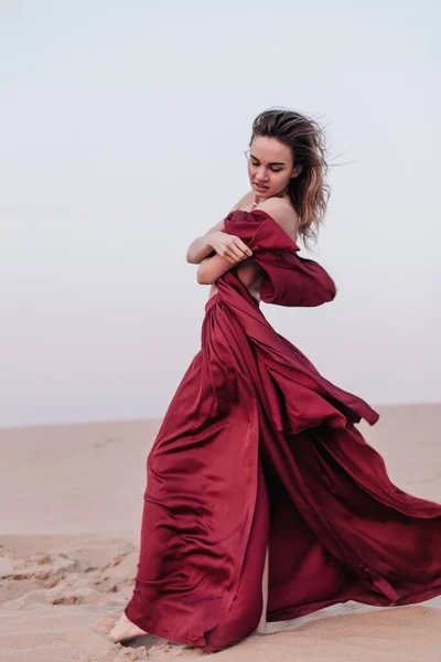 Girl with red cloth in the sunset rays in the desert