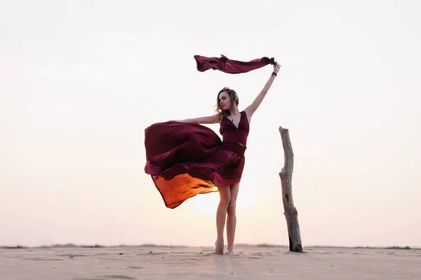 Silueta de una chica vestida de rojo al atardecer en el desierto — Foto de Stock