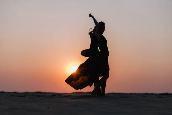 Силуэт девушки в красном платье на закате в пустыне — стоковое фото