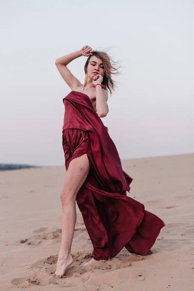 Chica con tela roja en los rayos del atardecer en el desierto —  Fotos de Stock