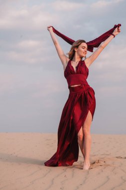 Çölde gün batımında kırmızı elbiseli bir kız.