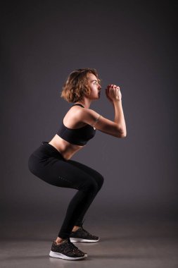 Siyah arka planda yoga yapan genç bir kız.