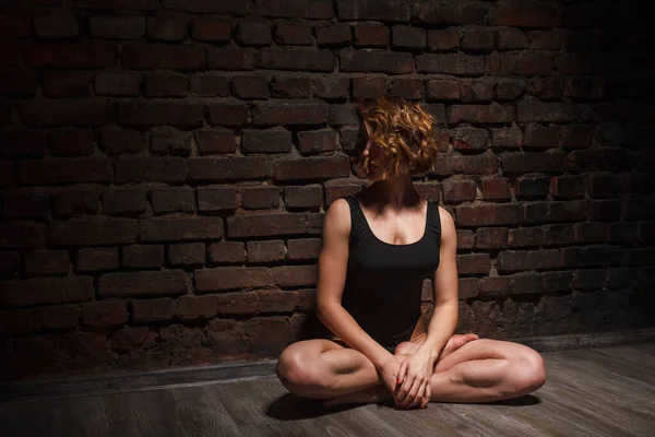 Girl in black swimsuit does yoga against the background of a brick wall — Stock Photo, Image