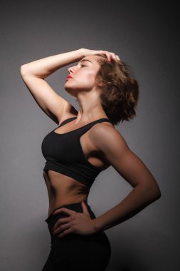 Siyah arka planda yoga yapan genç bir kız.
