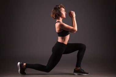 Siyah arka planda yoga yapan genç bir kız.