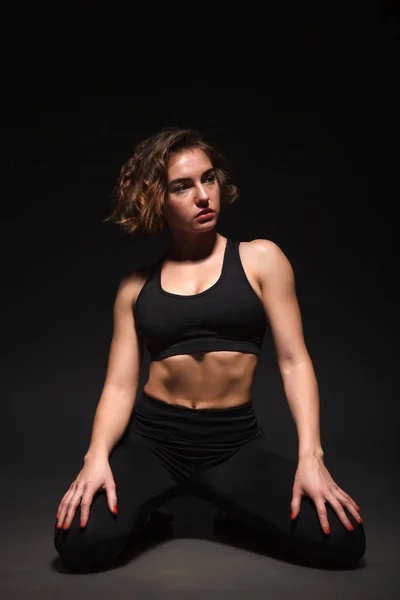 Chica joven haciendo yoga sobre un fondo negro — Foto de Stock