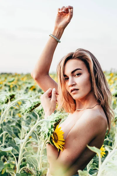 Une jeune fille seins nus se tient dans des tournesols — Photo