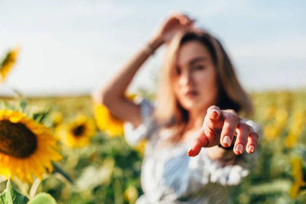 En ung flicka i skjorta står i solrosor — Stockfoto