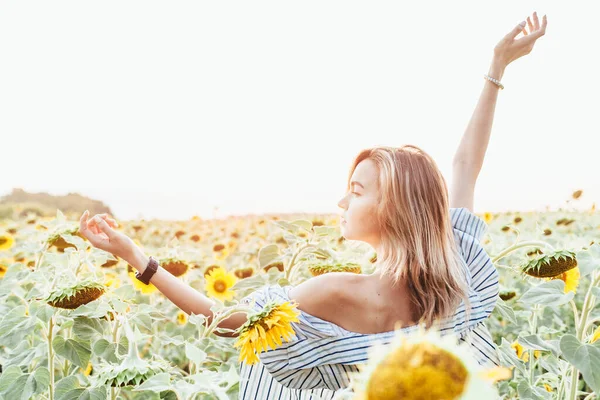 Tişörtlü genç bir kız ayçiçeklerinin içinde duruyor. — Stok fotoğraf