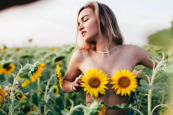 Genç üstsüz bir kız ayçiçeklerinde duruyor. — Stok fotoğraf