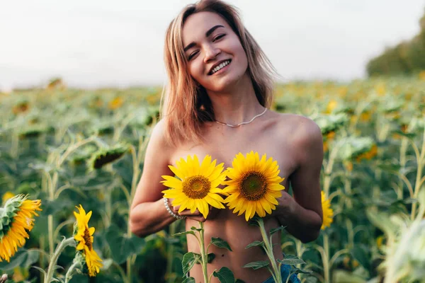 Une jeune fille seins nus se tient dans des tournesols — Photo