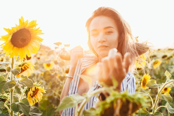 En ung flicka i skjorta står i solrosor — Stockfoto