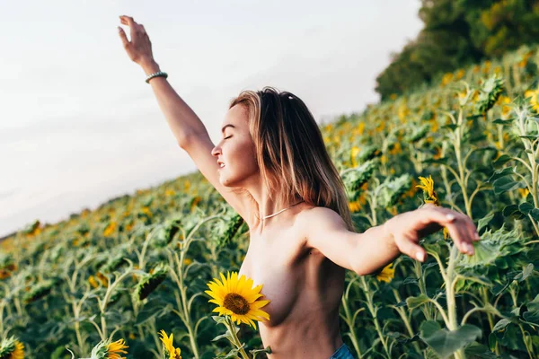 Mladá dívka nahoře bez stojí na slunečnicích — Stock fotografie