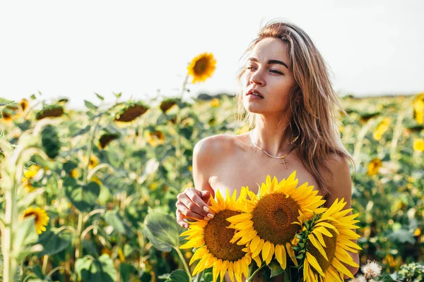 Mladá dívka nahoře bez stojí na slunečnicích — Stock fotografie