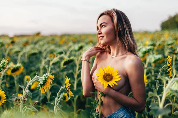 Genç üstsüz bir kız ayçiçeklerinde duruyor. — Stok fotoğraf